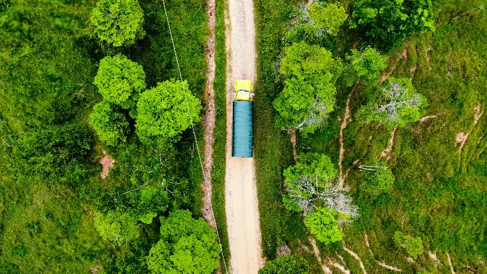 An aerial view of a dirt road surrounded by trees